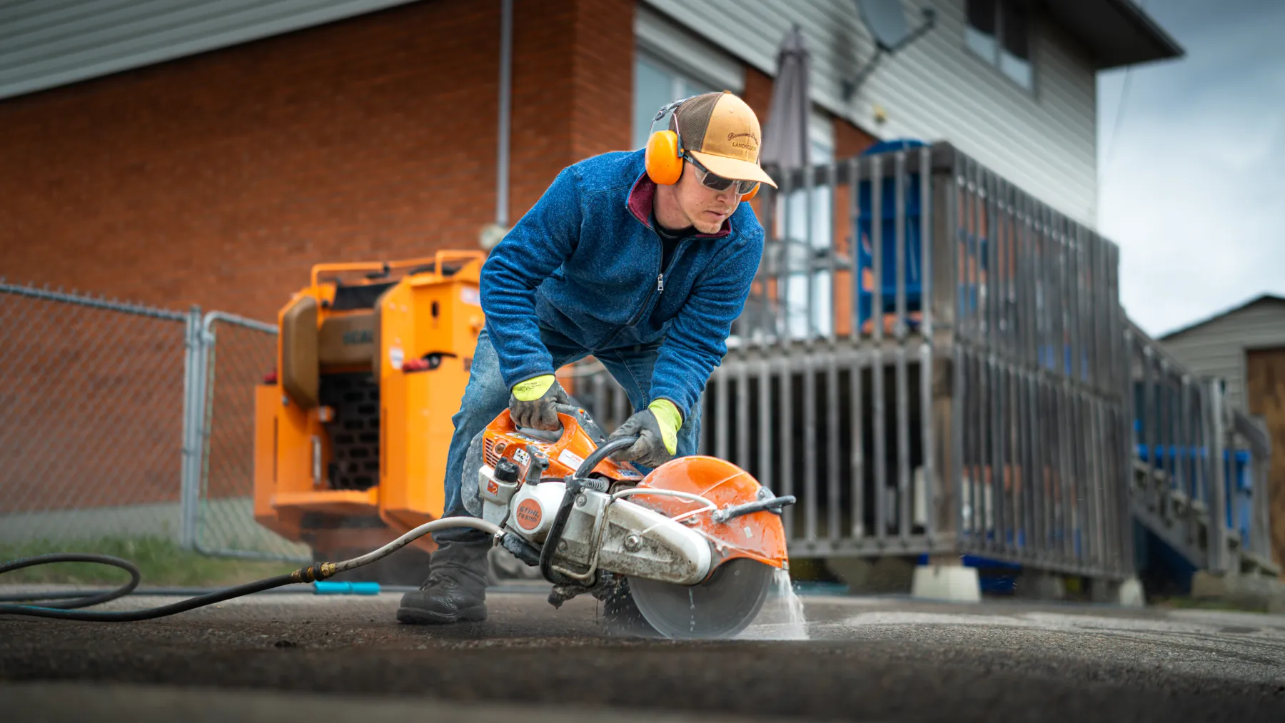 Bouwers crew member cutting an interlock paver on-site with a concrete saw, North Bay, Ontario.
