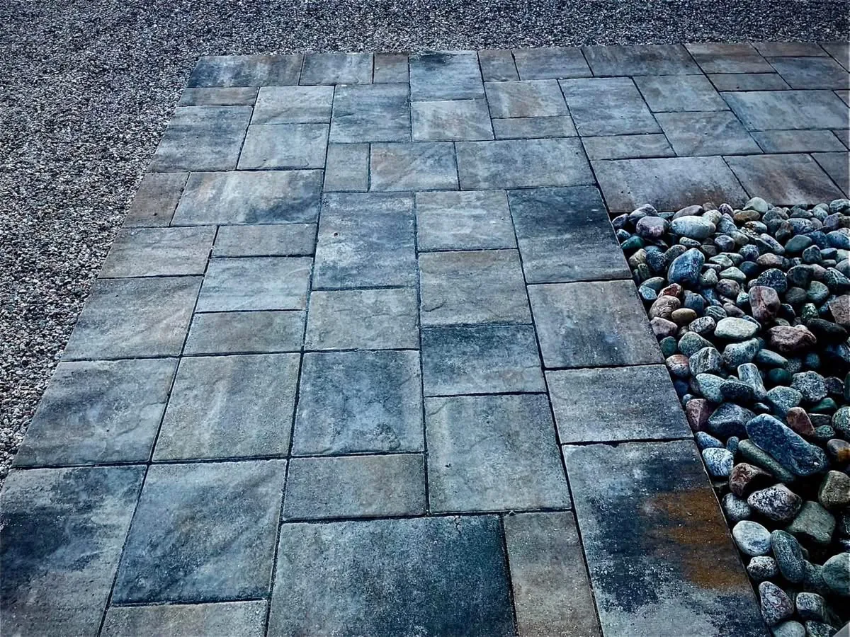 Permacon Mondrian Plus paver field detail with Margeau Beige edge transitioning to a decorative river-rock border, installed by Bouwers Design Landscaping on a North Bay residential project.
