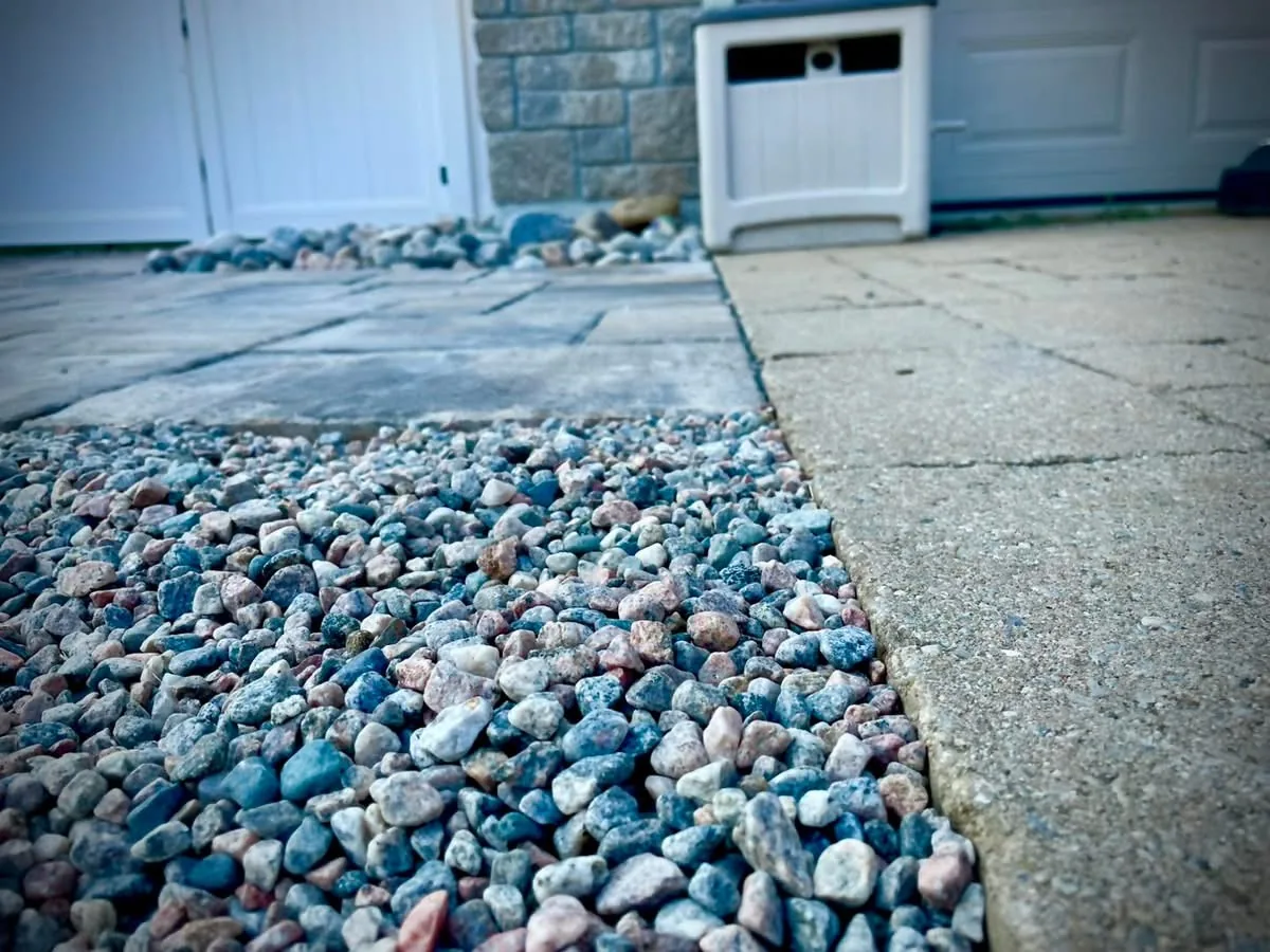 Decorative river-rock drainage detail beside a Bouwers Design Landscaping paver landing in North Bay.